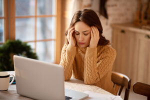 Woman stressed in front of laptop at home.